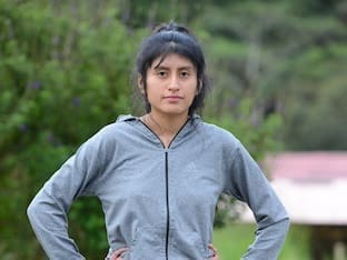 Alison standing outdoors in a gray zip-up sweatshirt, hands on hips, with a calm and serious expression.
